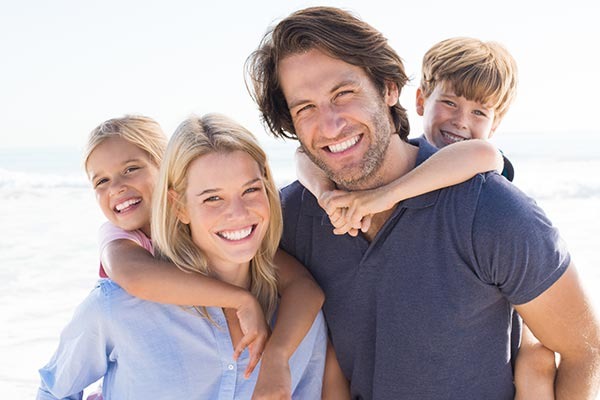Smiling parents carrying their children on their backs during family preventive care