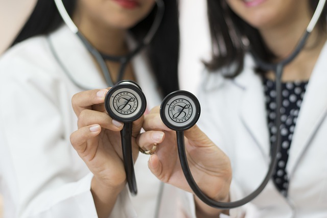 Two female doctors holding stethoscopes during a physical exam consultation